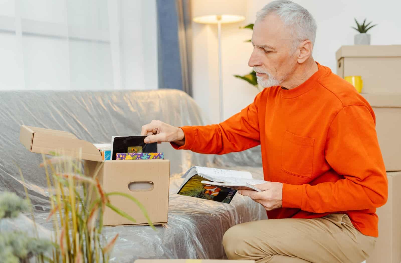 A senior packs a small box of photos to take to the senior living community.