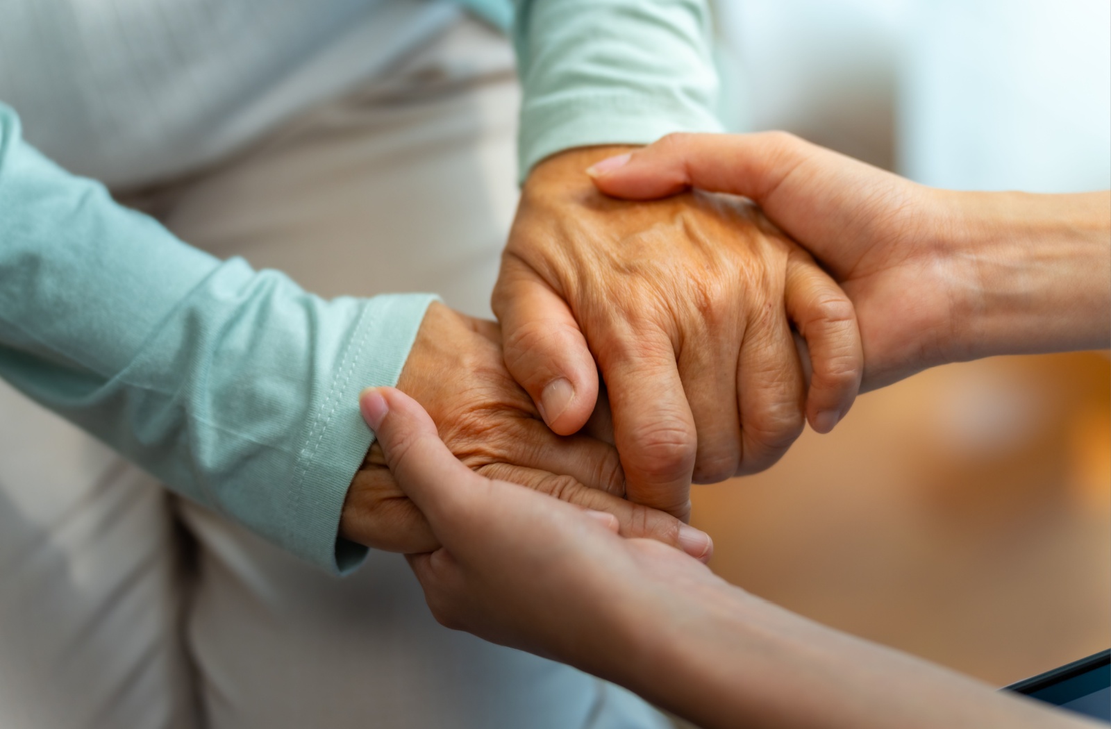 A close-up of an elderly person's hands being held by a younger person