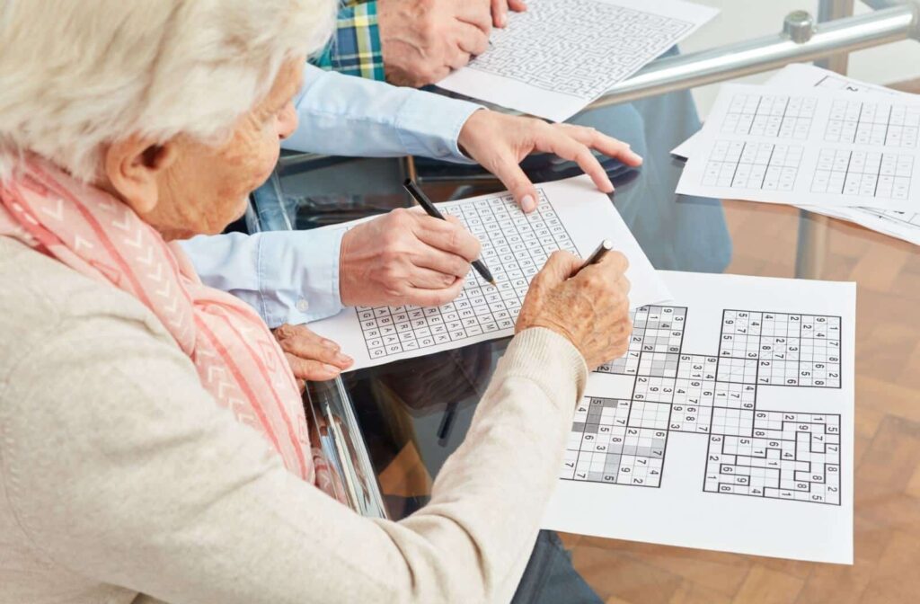 Two memory care friends completing a brain puzzle together.